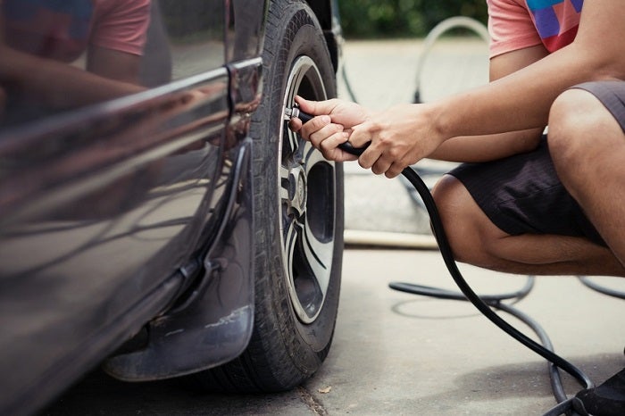 Man driver checking air pressure and filling air in the tires of