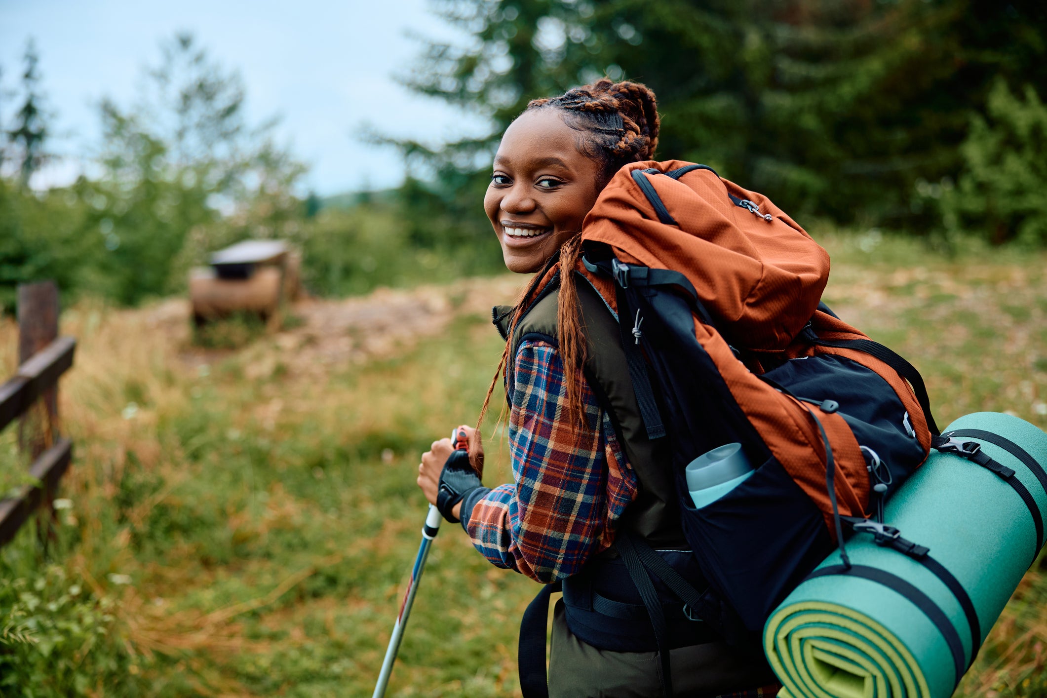 Happy black woman hiking in the mountains and looking at camera.