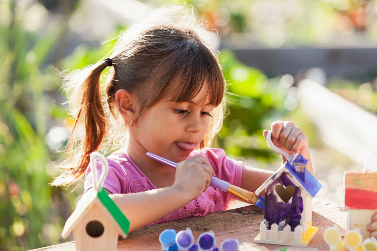 Little girl painting bird house