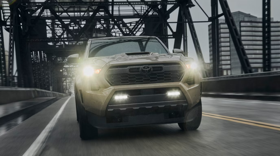 Front profile of a 2026 Toyota Tacoma hybrid driving along Route 41 in Waukegan showing its bold grille and high ground clearance