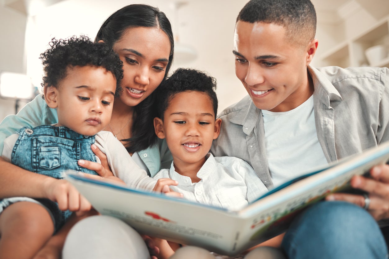 Shot of a young family reading a book together on the sofa at home