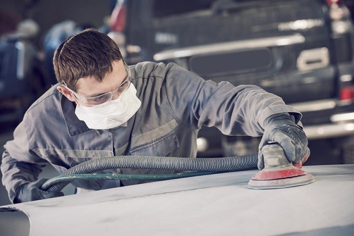 auto repairman grinding autobody bonnet