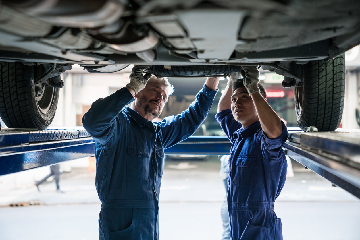Mature car mechanic and apprentice at work