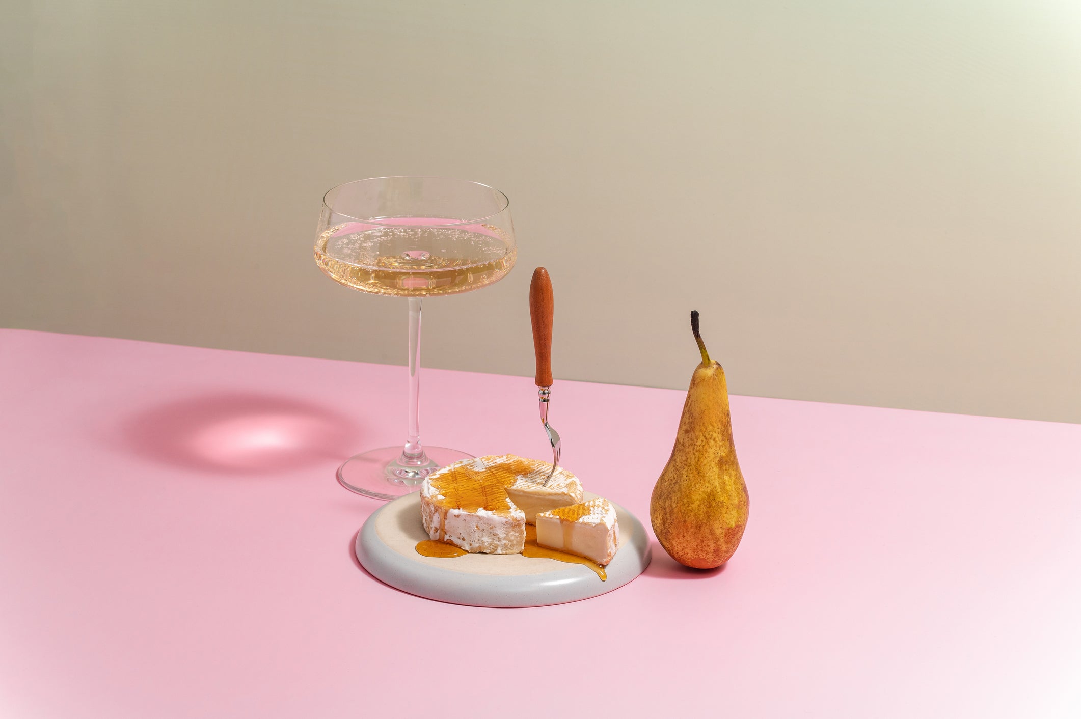 brie cheese on a plate with honey and pear, champagne in a glass