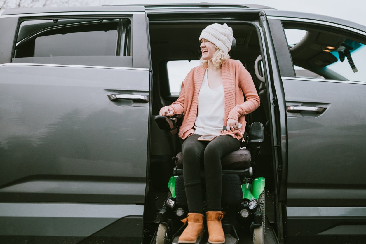 Cheerful Young Woman In Wheelchair Entering Vehicle