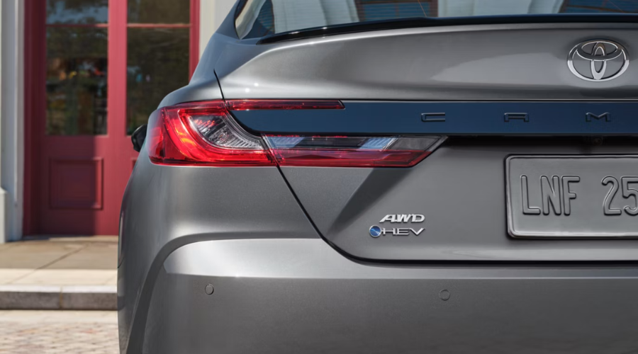 Close-up of the rear taillights, AWD, and HEV hybrid badges on a gray 2026 Toyota Camry parked in Libertyville, IL