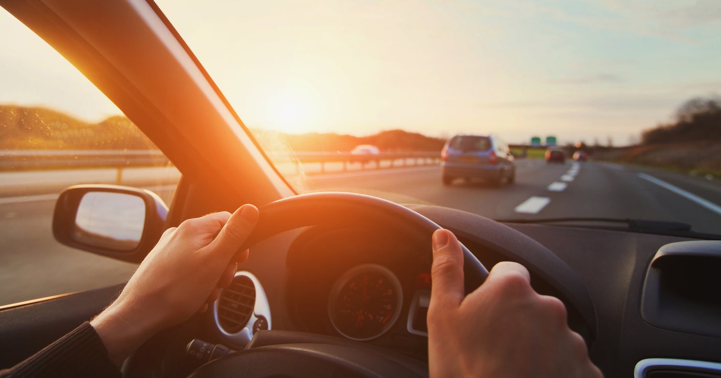 hands of car driver on steering wheel, road trip