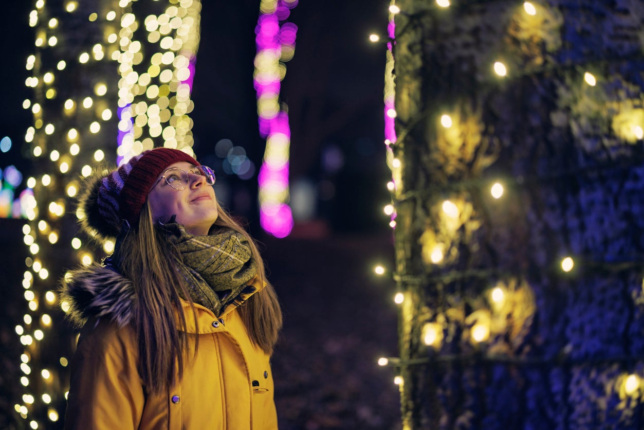 Teenage girl is looking at the Christmas lights in public park