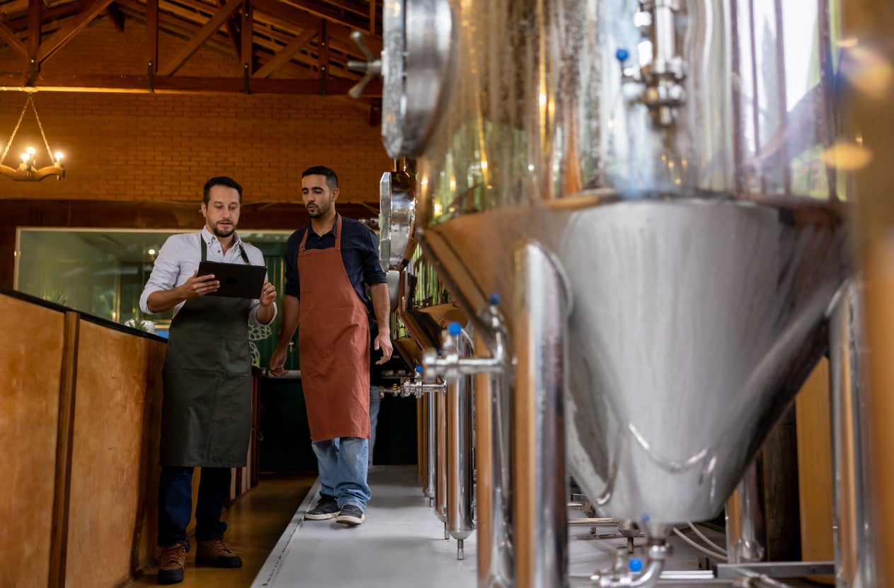 Team of men working at a brewery and controlling the production line