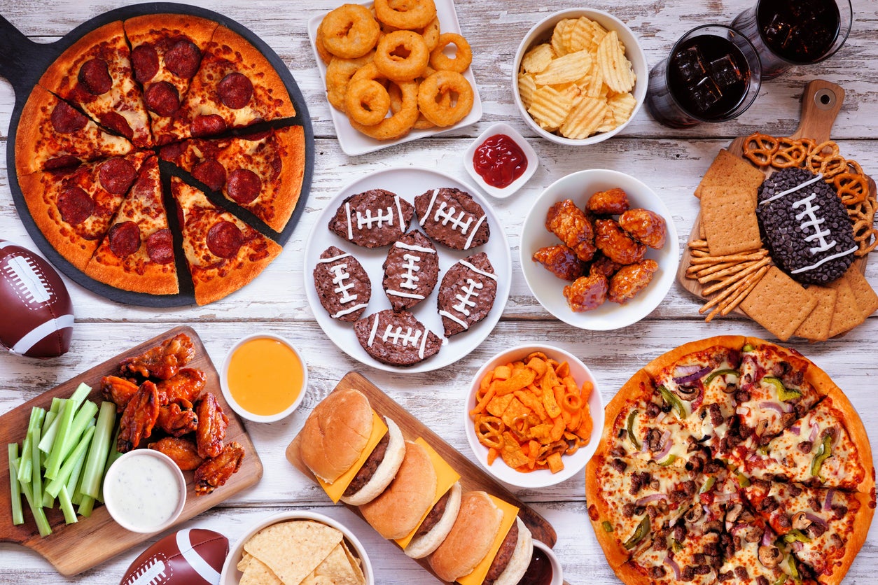 Super Bowl or football theme food table scene, above view on white wood