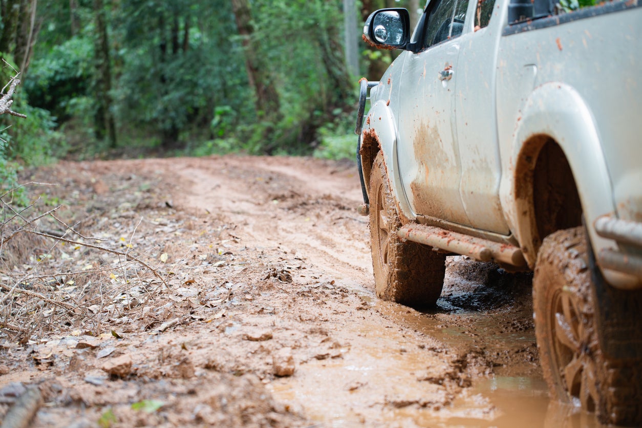 Dirty offroad car, SUV covered with mud on countryside road, Off-road tires, offroad travel and driving concept.