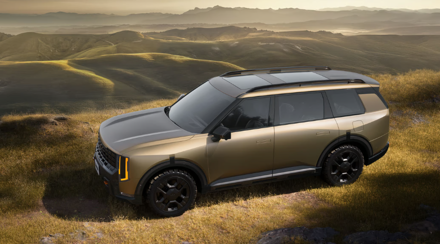 High-angle view of a bronze 2026 Kia Telluride X-Pro with black off-road wheels, all-terrain tires, and roof rails parked on a grassy ridge during autumn golden hour, representing the ideal 2026 Kia Telluride towing setup for fall camping trips across Waukegan, Gurnee, and Lake County IL.