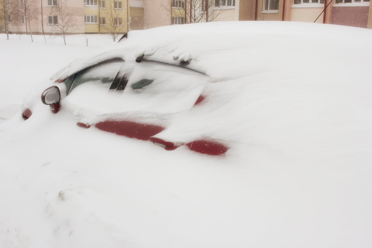 Red car under a large snowdrift, snow storm, winter, blizzard, storm warning, drift