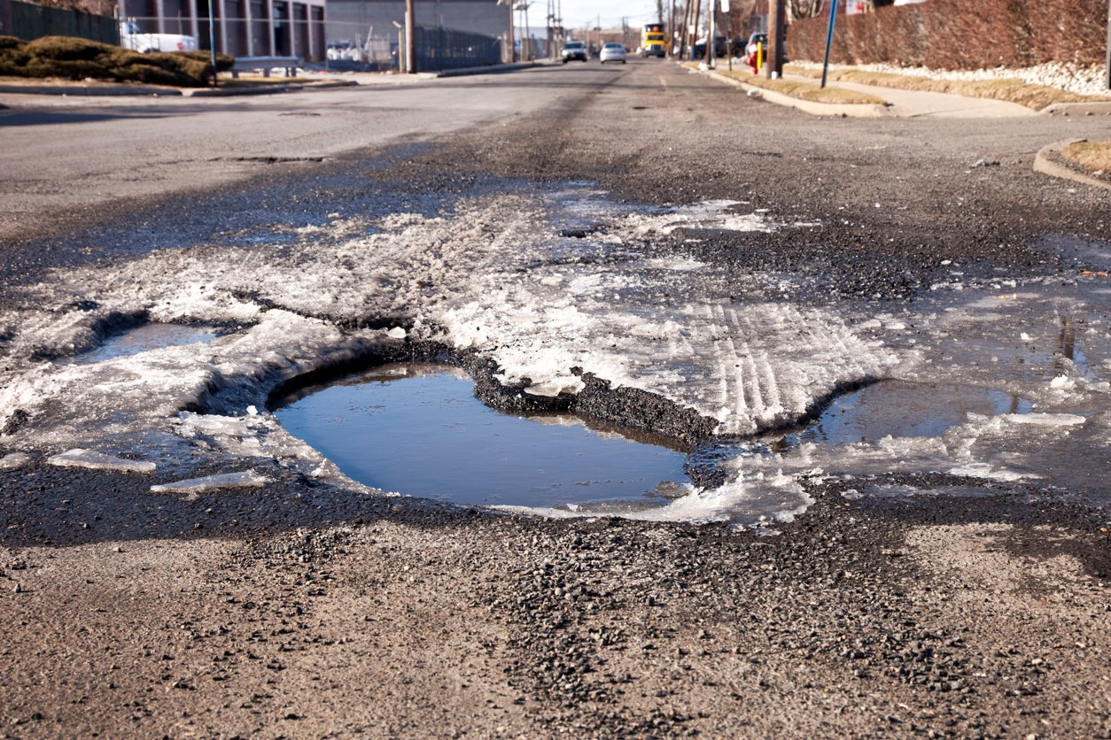 Large pothole with water and ice in the road