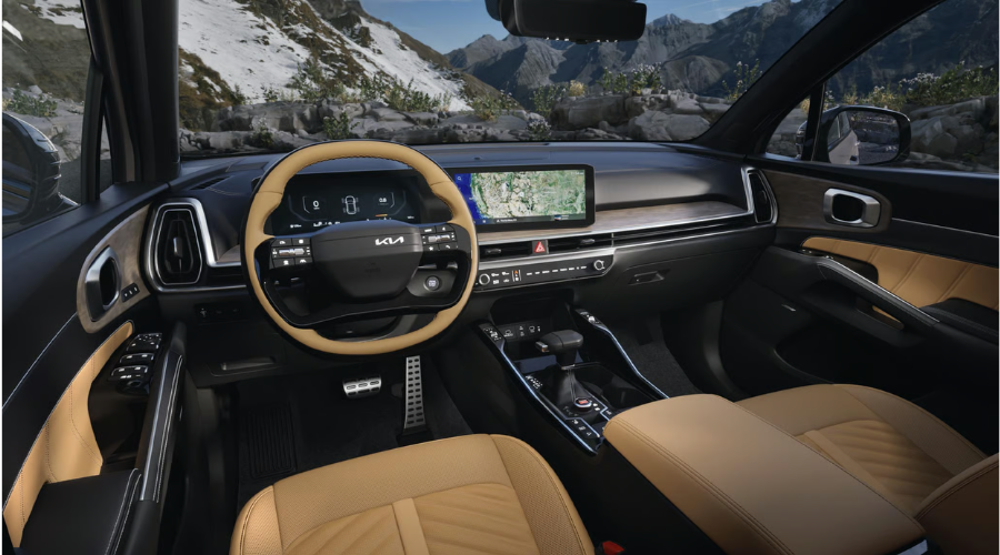 Front interior cockpit of the 2026 Kia Sorento featuring tan leather seating, a two-tone leather steering wheel, and dual widescreen digital displays with GPS navigation for drives along I-94 and US-41 near Waukegan and Gurnee, IL.