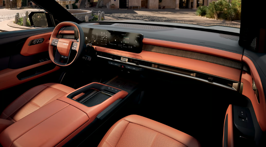 Modern interior cabin view of the 2026 Kia Telluride featuring terracotta leather seats, a wide panoramic digital infotainment screen, leather-wrapped steering wheel, and warm wood dashboard trim, offering premium comfort and navigation tech for autumn highway drives across Waukegan and Gurnee IL.