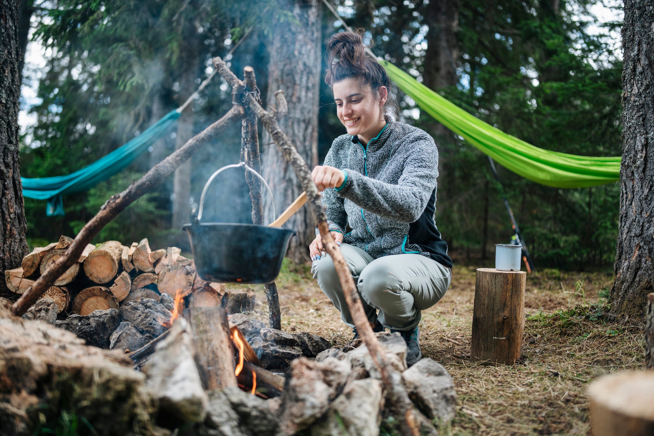 Woman cooking meal on the campfire.