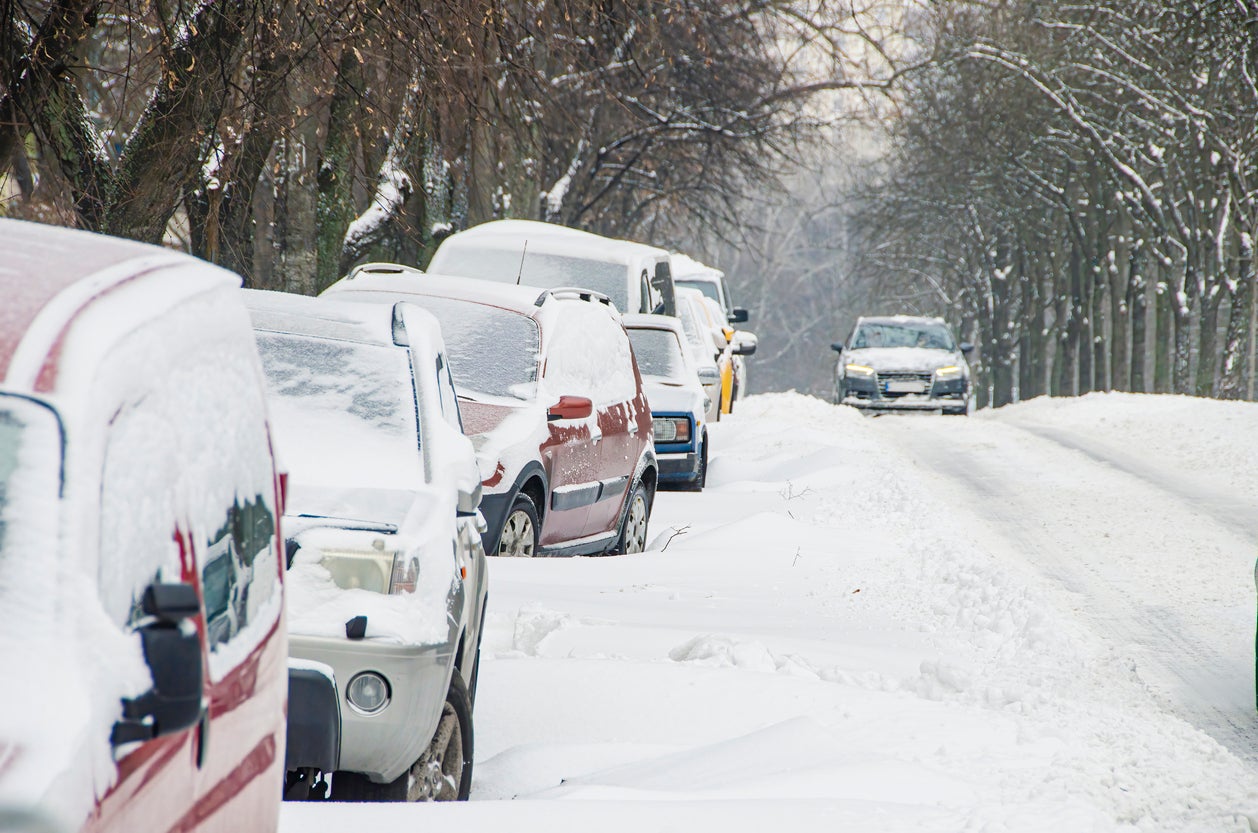 Slippery road covered by snow and cars parked in the snowdrifts. Bad weather for driving in the city. Traffic jams and collapse