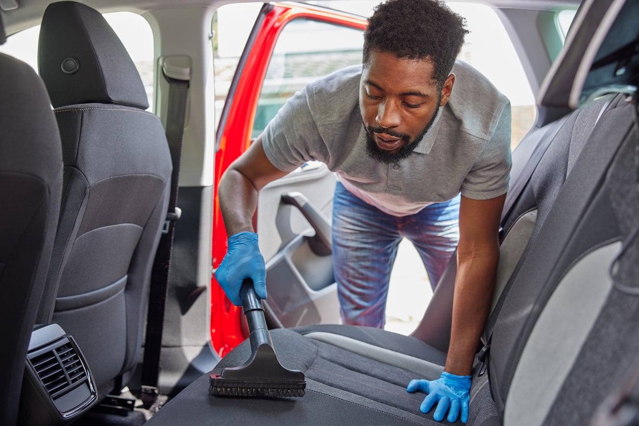 Man Hoovering And Cleaning Rear Seats Of Car During Car Valet