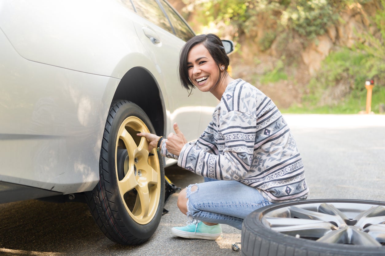 Young Women Changing A Flat Tire