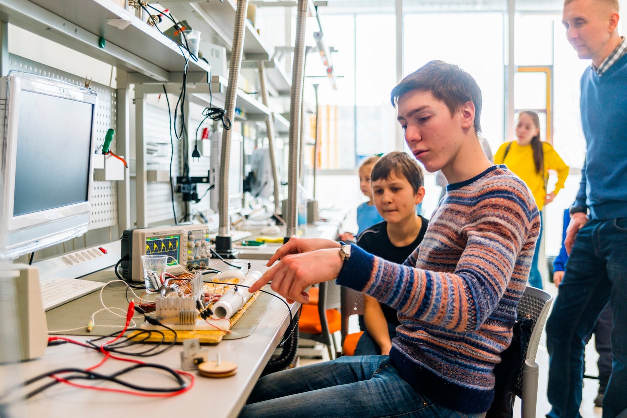 The group of kids of different ages, boys, and girls, working in the engineering laboratory