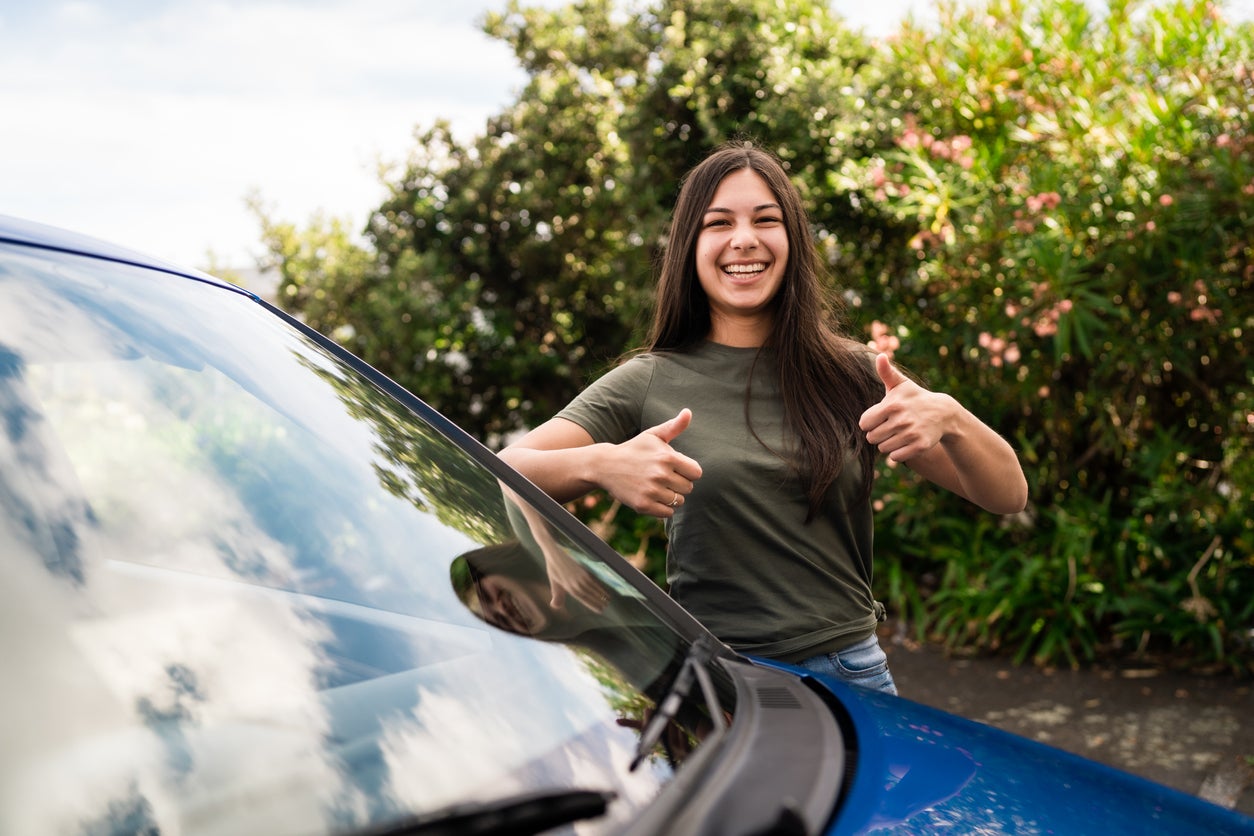 Happy woman with thumbs up to buy a new car.