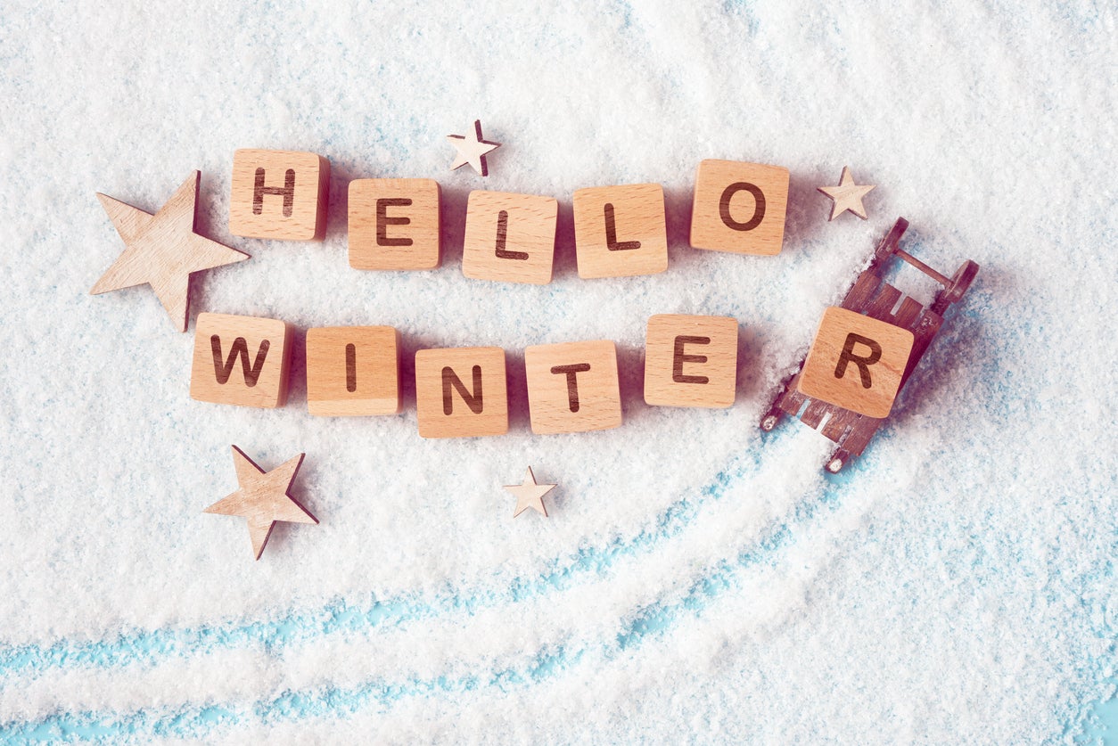 Wooden blocks with Hello Winter lettering on a snowy background. The concept of upcoming winter holiday season