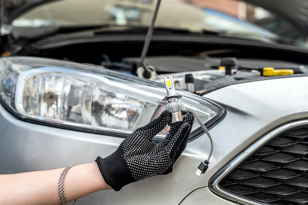 male hand holding modern LED h7 bukb near headlamp