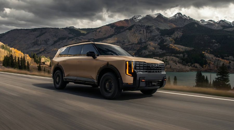 2027 Kia Telluride HEV driving through a scenic Illinois road showing its bold redesign and hybrid efficiency Classic Kia in Waukegan, IL