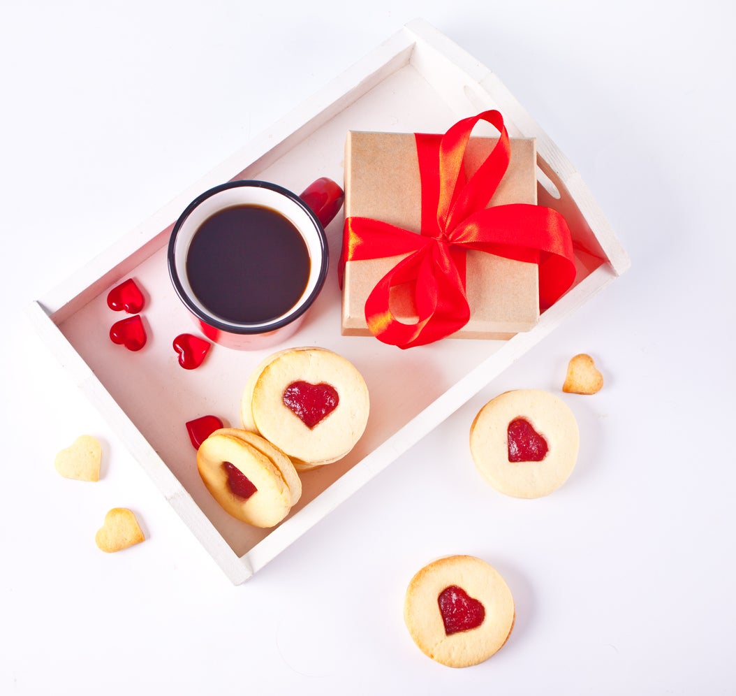 Heart shaped traditional linzer cookies with strawberry jam, mug of coffee and gift box. Valentine s day concept.