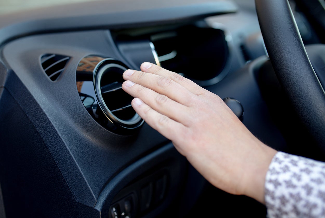 Driver hand on air ventilation grille with power regulator, modern car interior detail