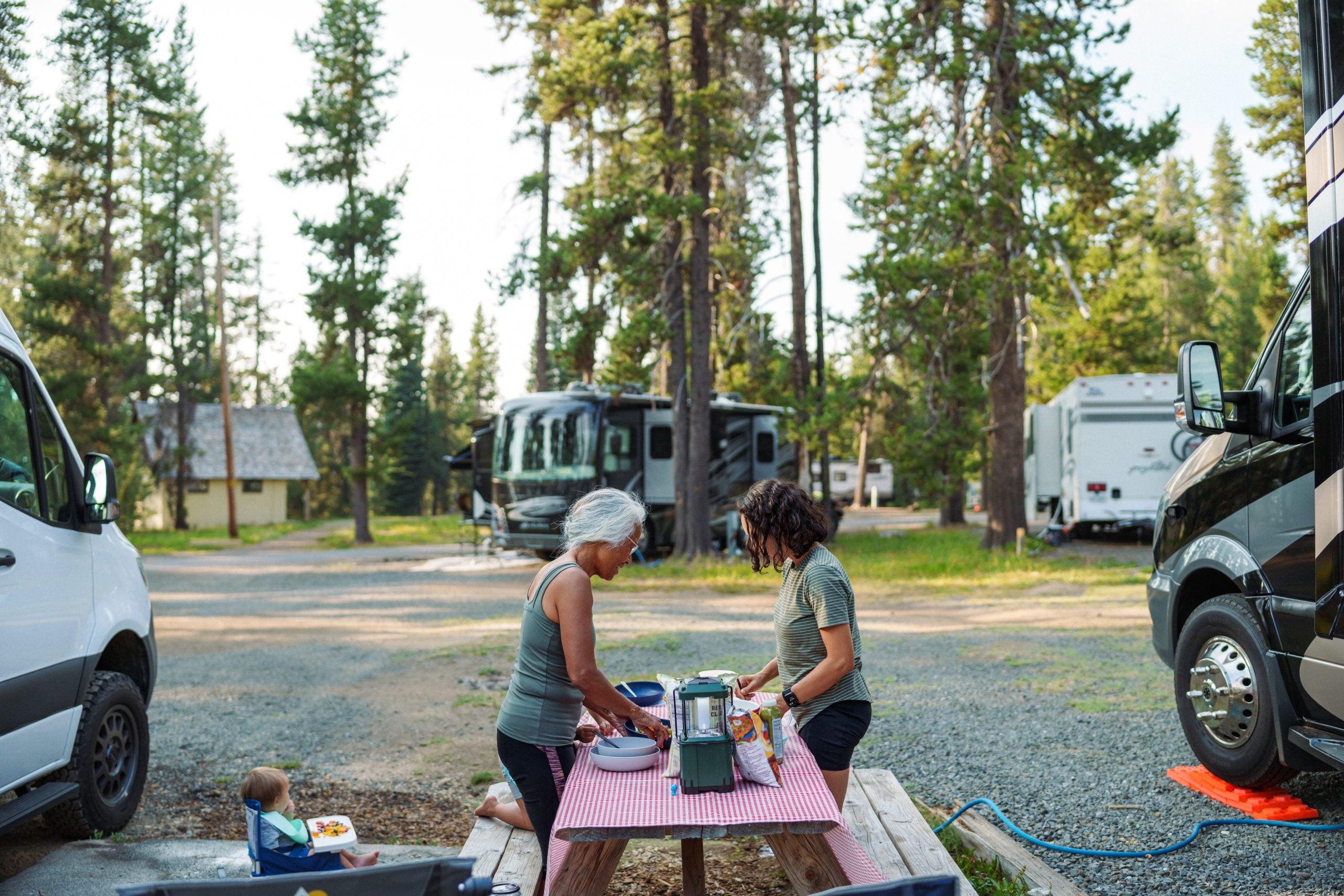 Active senior woman preparing meal outdoors while on camping trip with her multi-generation family
