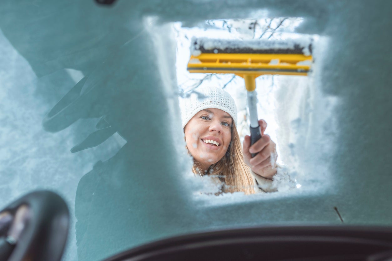 Woman clean car of snow view from inside