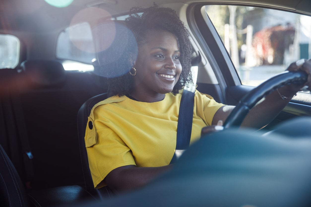 Charming young woman sitting in driver's seat in her car and enjoying a ride