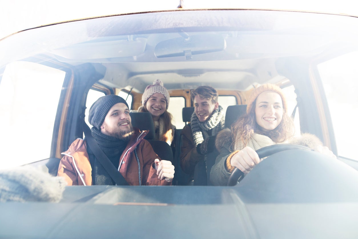 Group of four friends travelling by car in winter nature.
