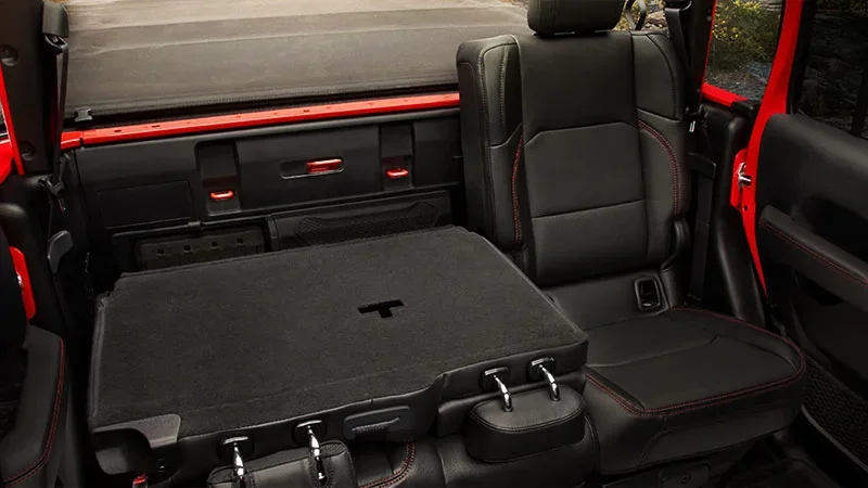Image shows the back seats of a red 2023 Jeep Gladiator folded down showing anker points to tie things down to.