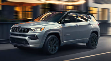 Jeep Compass driving down a main street.