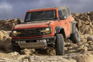Blood Orange and soft top 2022 Ford Bronco driving over an extremely rocky terrain.