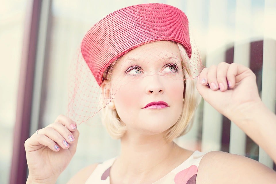Blonde woman in a vintage pink hat with a net veil