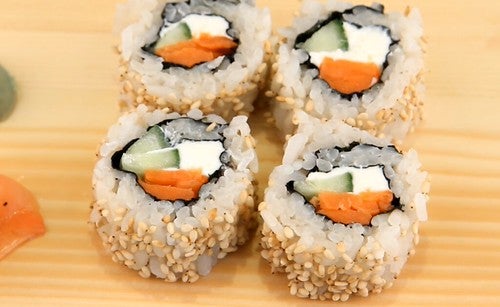 California rolls on a wooden cutting board next to pieces of sashimi