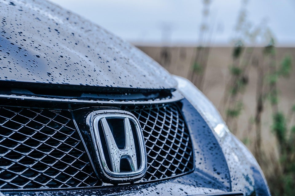 Close up shot of the Honda logo on the front of a car after it rained
