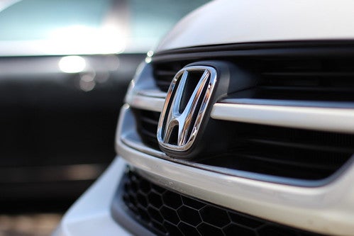 Close on grille of white Honda CR-V with Honda logo and blurred background