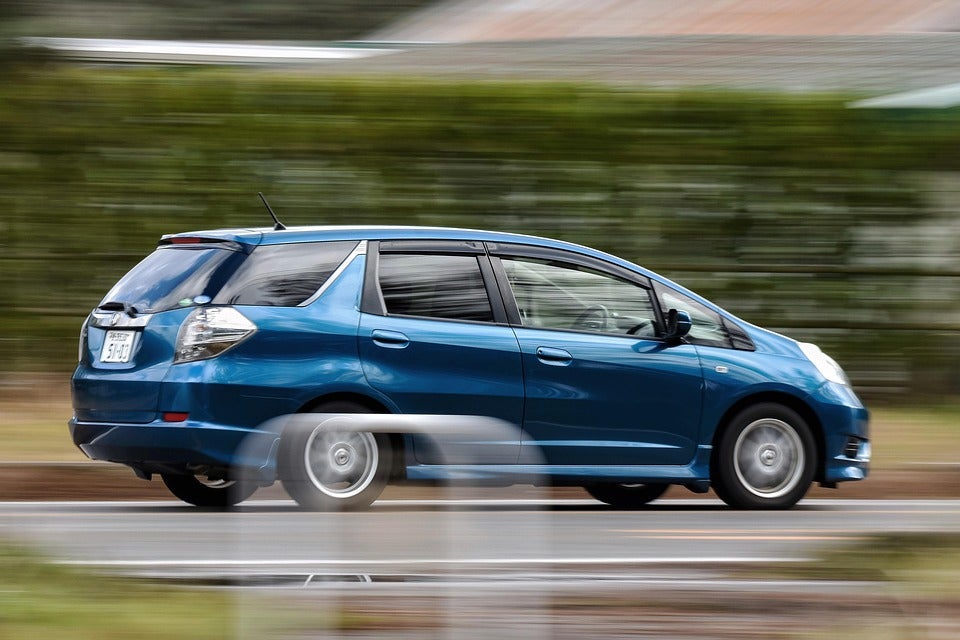 Blue Honda driving by trees