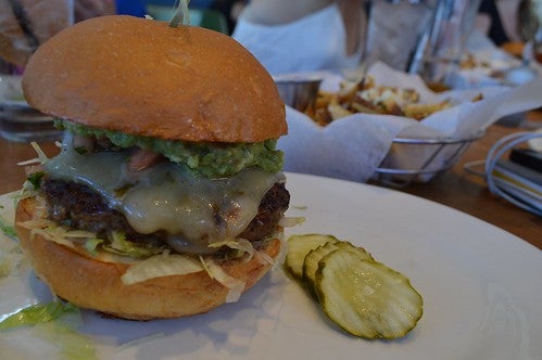 Handcrafted burger with cheese and pickles on the side