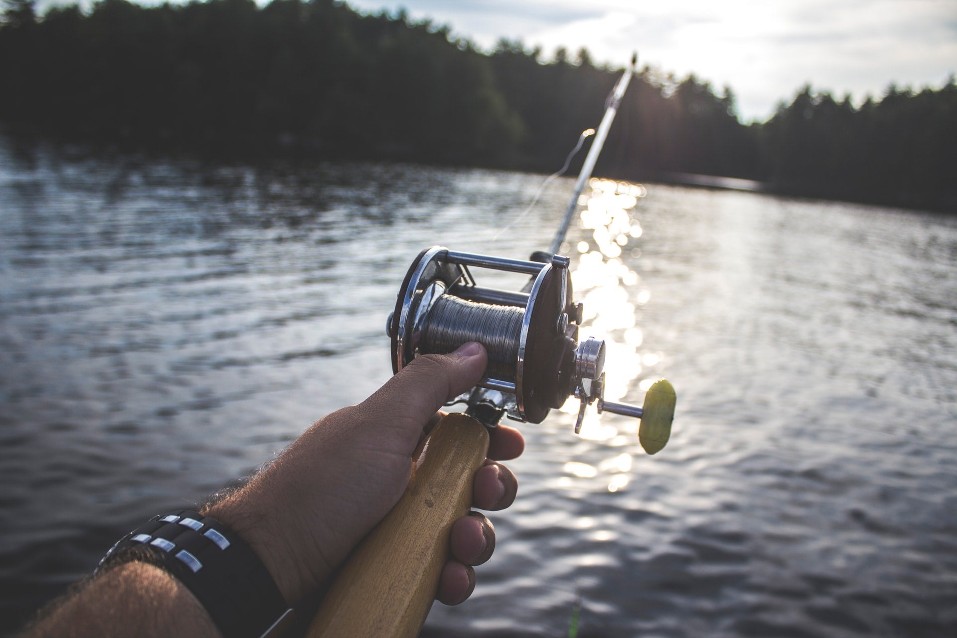 Close on fishing rod that's been cast, held in left hand
