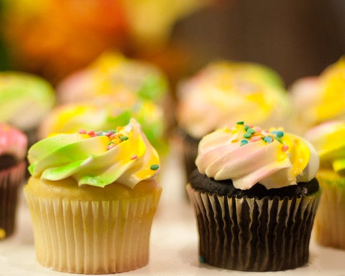 Small white and black cupcakes with whipped cream on top