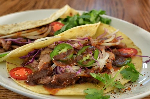 Pork Tacos with peppers, lettuce, cilantro and sauce