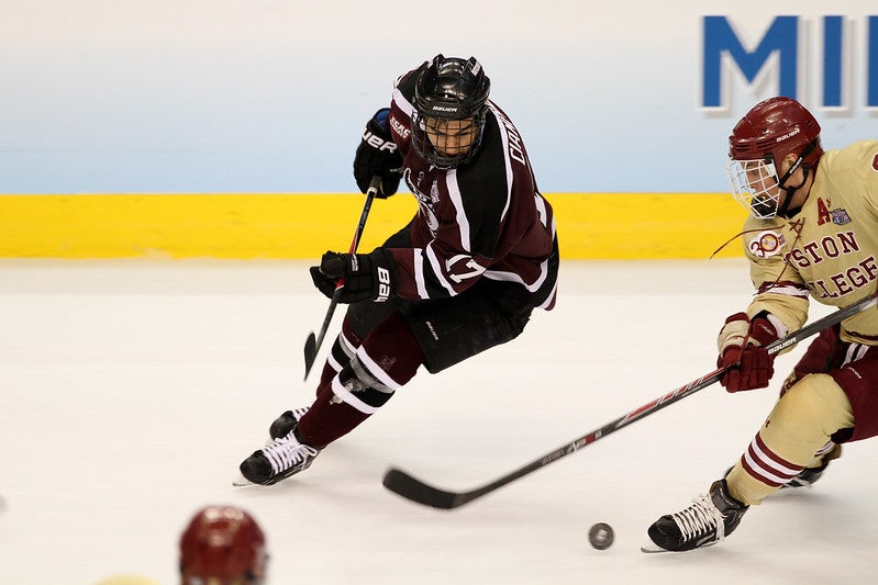 College hockey players on opposing teams go for the puck
