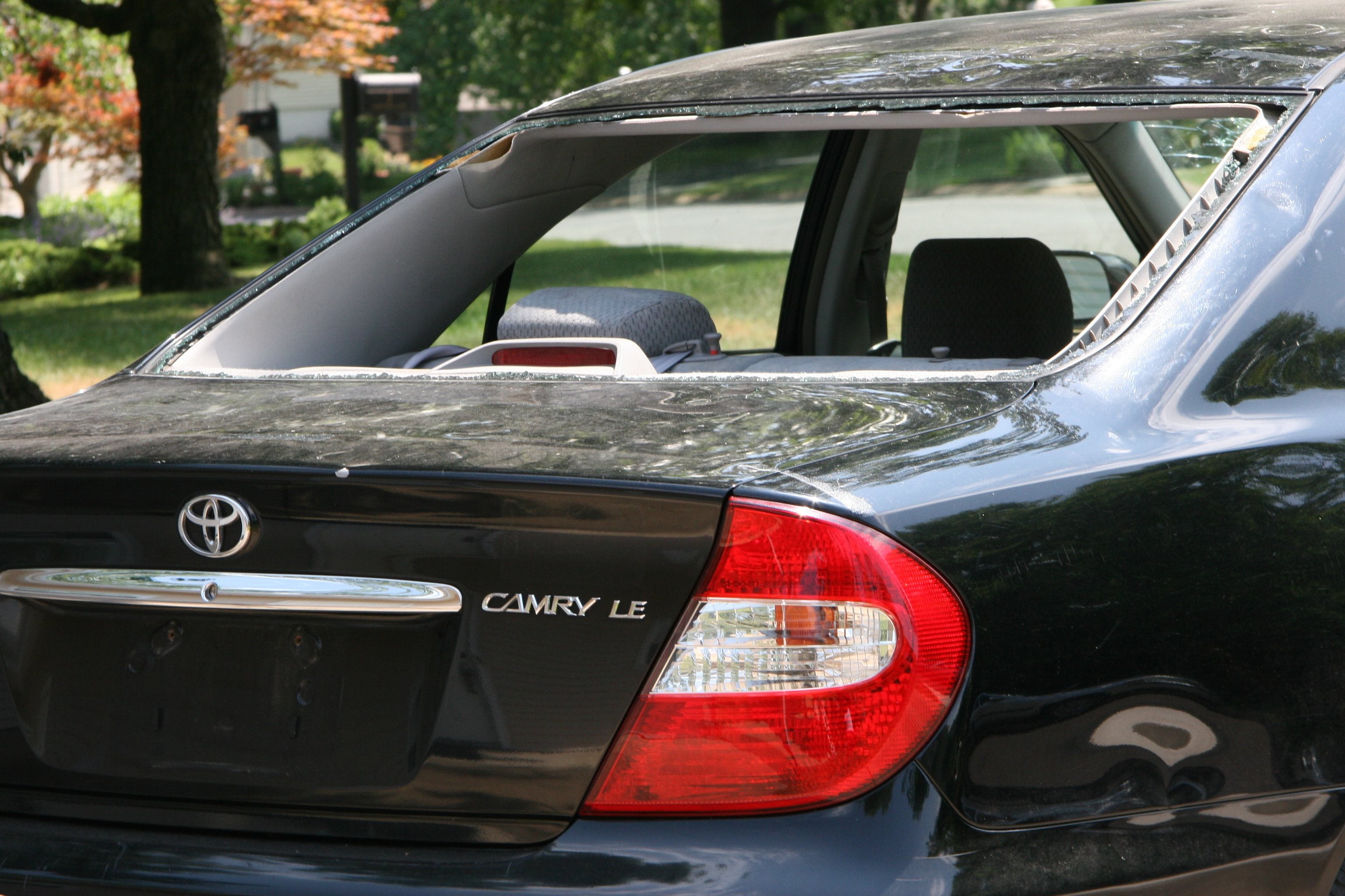 Black Toyota Camry LE with hail damage on rear