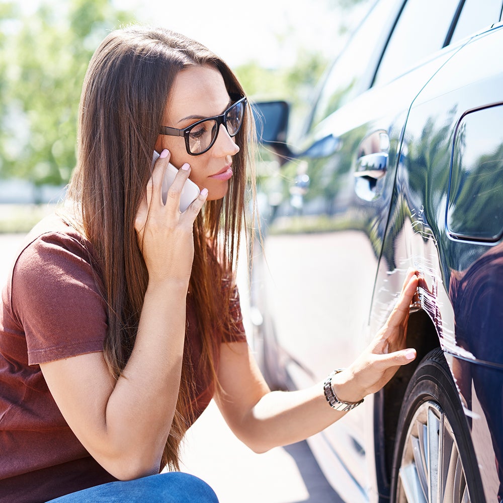 Student examining a small scrape on her car
